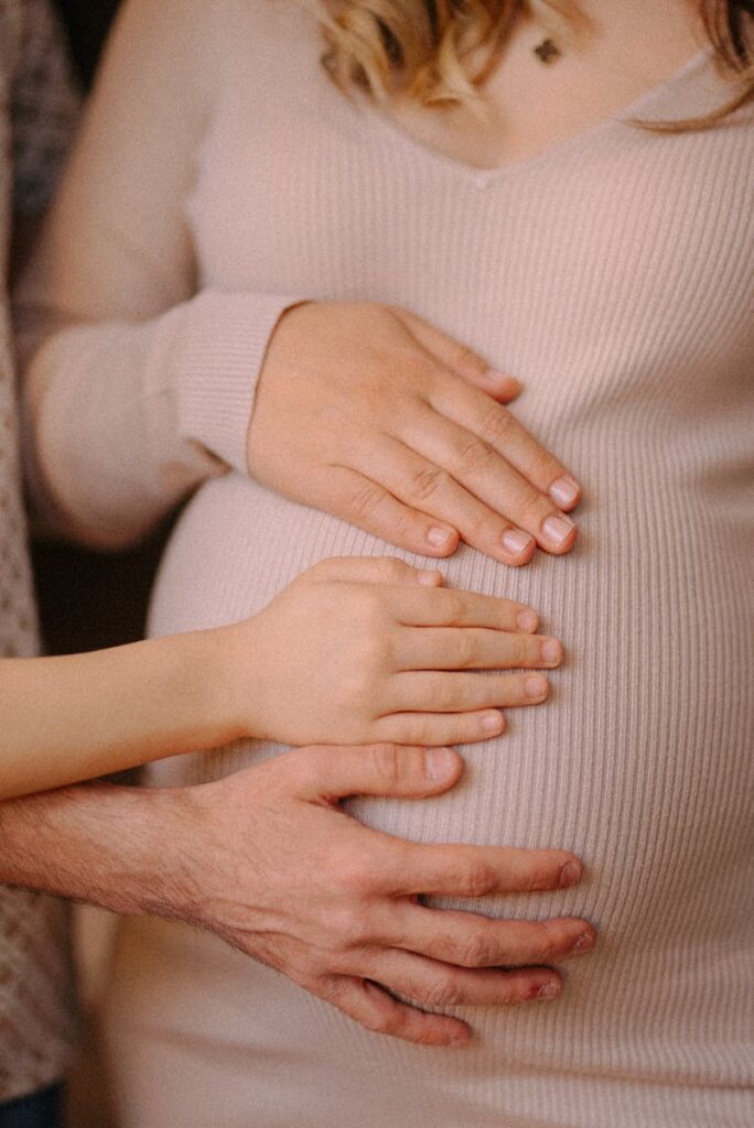Close-up of family hands on pregnant belly, symbolizing love and togetherness.
