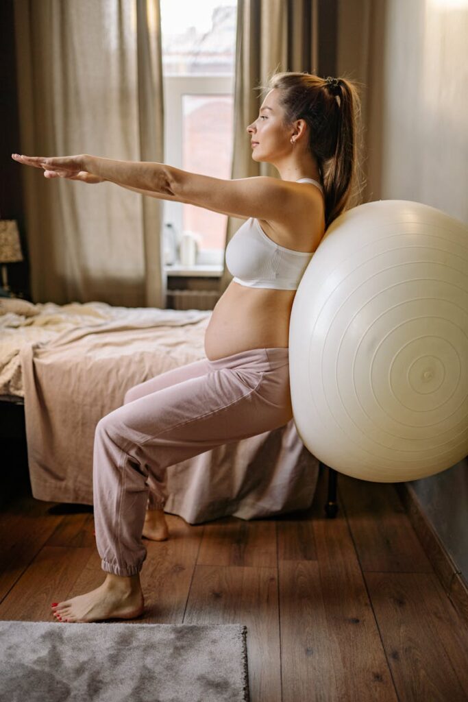 Expectant mother practicing balance exercises with a stability ball indoors. Healthy pregnancy lifestyle.